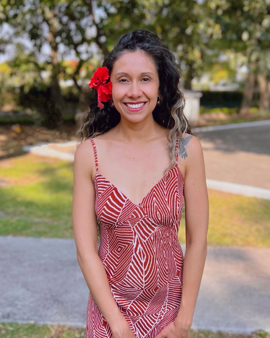 Paulina Rosas sonriendo en un jardín, con una flor roja en el cabello